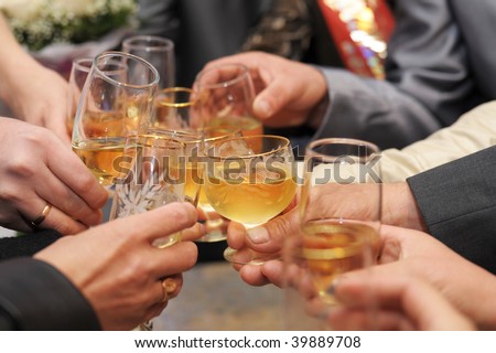 glasses with champagne in hands being clinked during drinking toast
