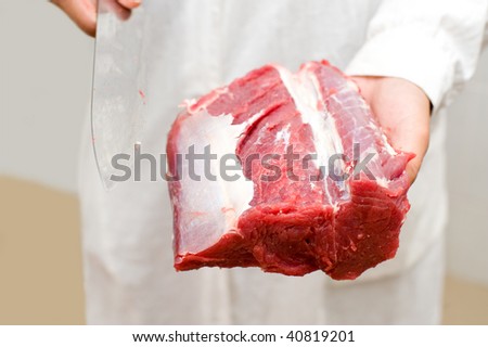 piece of fresh beef and knife in butchers hands