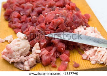 cut beef and fat on wooden hardboard with knife blade in shallow DOF
