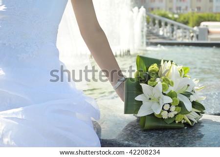 bouquet of white lilies in brides hand sitting at fountain