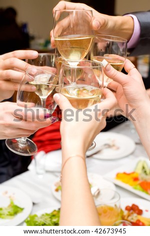 glasses with champagne in hands being clinked during drinking toast