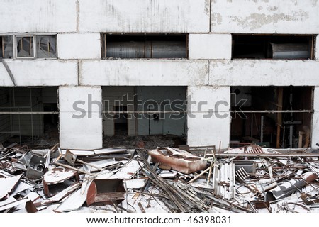 wall of deserted house with pile of litter covered with snow in front