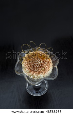 ice cream in glass bowl dusted with chocolate and decorated with caramel curl