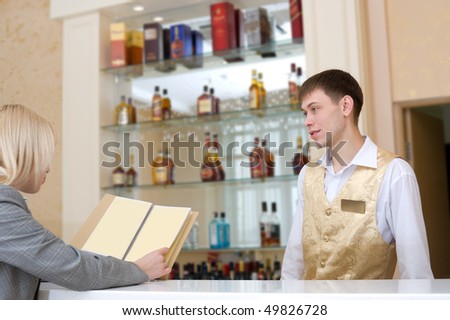 barman and blonde woman with wine list at restaurant bar
