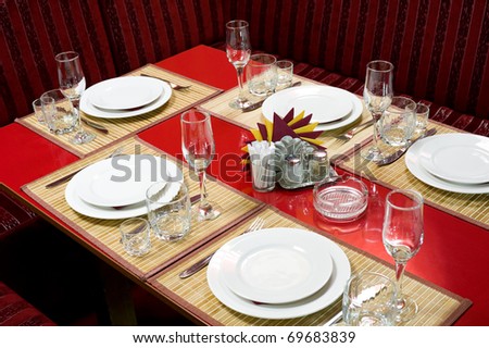 a laid red restaurant table for five persons