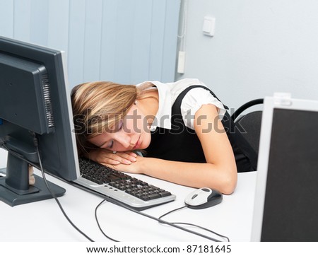 a young caucasian woman sleeps at her computer on a desk