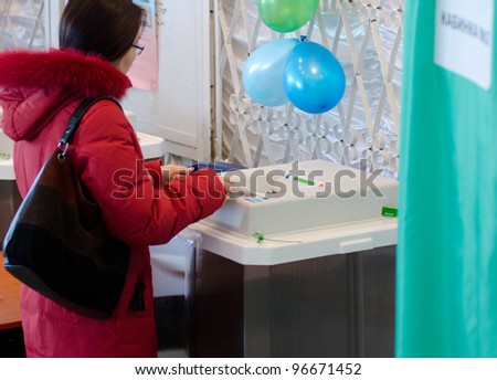 A woman drops a ballot for voting into an electronic ballot box at the presidential election of Russian Federation