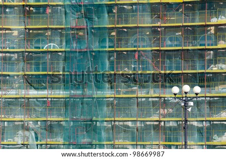architectural restoration - an old building in green mesh and scaffolding
