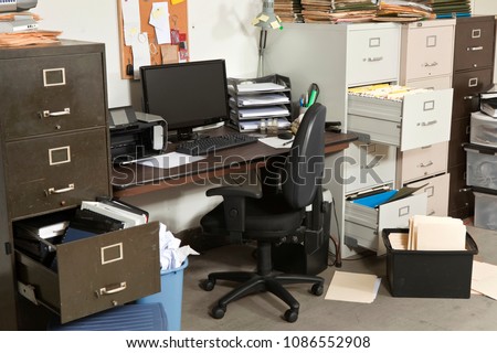 Messy office with piles of files and disorganized clutter.