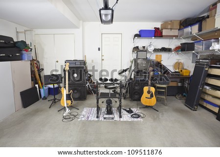 Rock band music equipment in a cluttered suburban garage.
