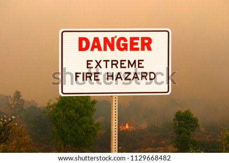 Danger extreme fire hazard sign with wildfire background.
