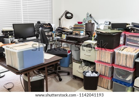 Messy business office with cluttered desk and boxes full of files.