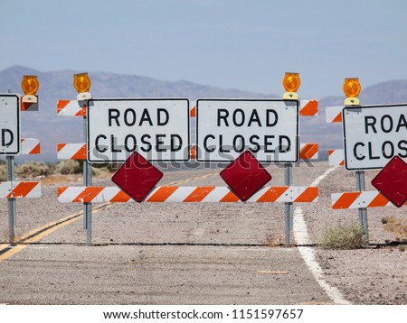 Highway road closure signs and barricades near Route 66 in the California Mojave Desert.
