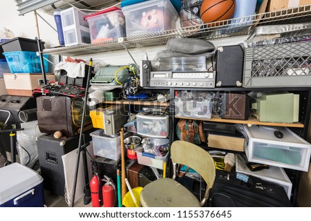 Full shelves of vintage electronics, boxes and sports equipment in typical suburban garage.