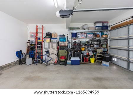 Cluttered but organized clean suburban residential two car garage with tools, file cabinets and sports equipment.
