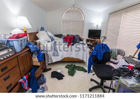 Messy, cluttered teenage boy\'s bedroom with piles of clothes, music and sports equipment.