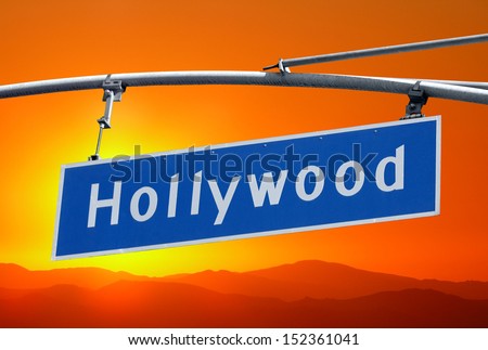 Hollywood Blvd street sign  and mountains with orange sunset sky.