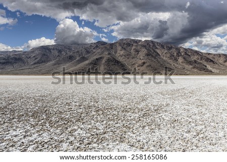 Mojave desert dry lake salt flat with dark storm clouds.