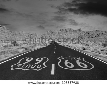 Route 66 black and white pavement sign with Mojave desert background.