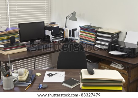 Busy, messy corner office with piles of files.
