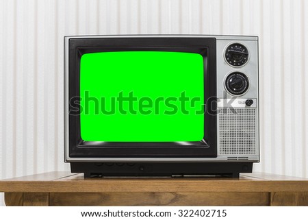 Old portable television set on vintage wood table with chroma key green screen.