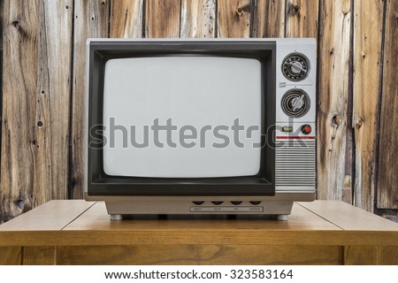 Vintage portable television and table with rustic cabin wall.