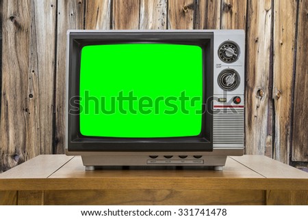 Vintage portable television with chroma key green screen and rustic cabin wall.