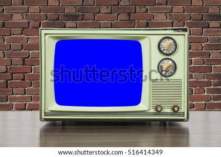 Grungy green vintage television set with brick wall and chroma key blue screen.