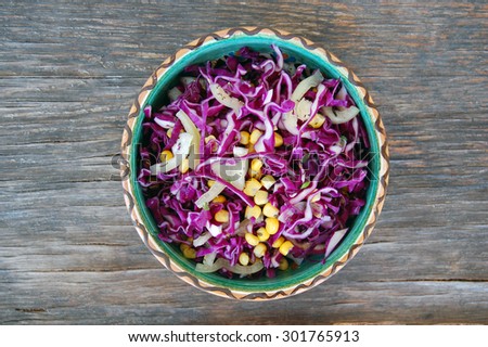 fresh red cabbage salad with sweet corn in ceramic bowl on rustic wooden table
