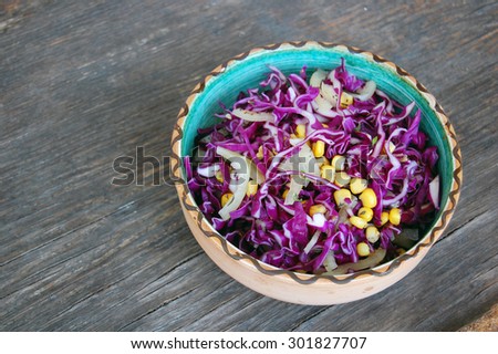 fresh red cabbage salad with sweet corn in ceramic bowl on rustic wooden table