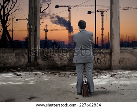 Businessman looking industrial place at sunset