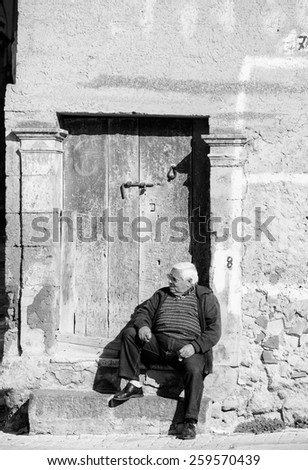 LEONFORTE, ITALY - JANUARY, 08: Old man sitting on the step of old door on January 08, 2014