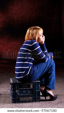 Girl sitting on the stool on dark background