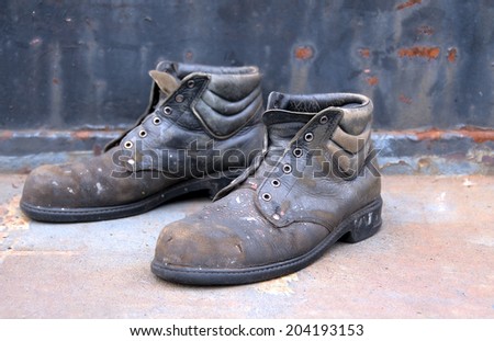 Old worn out work shoes  against a brown rusty background