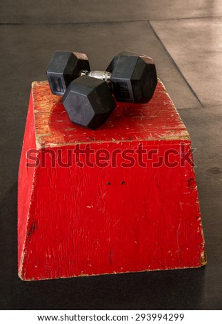 Red jump box with a pair of dumbbells