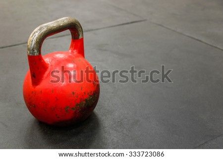 Close-up of red kettle bell on black gym floor