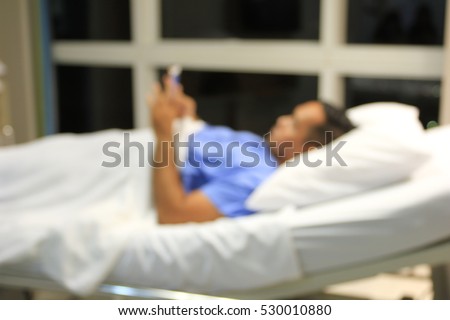 Blurred background Male Patient use smartphone on bed in hospital .