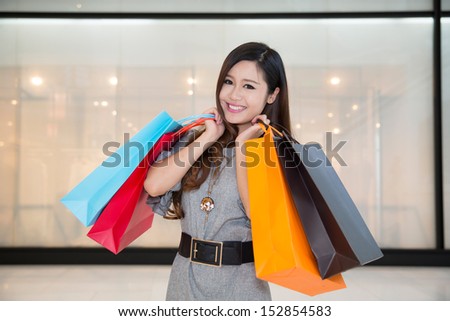 woman with shopping bags in mall, wearing a shirt
