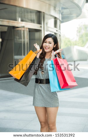 young woman carrying shopping bags and smiling outside the mall