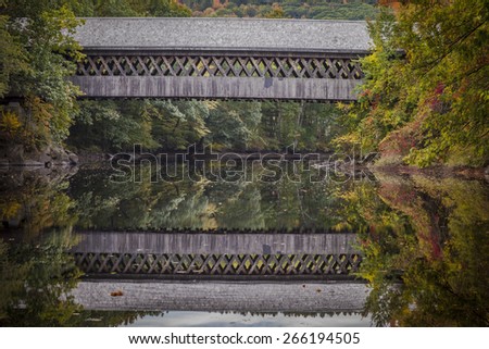 Covered foot bridge spanning the Contoocook River at Henniker, New Hampshire is framed by beautiful colors of autumn foliage