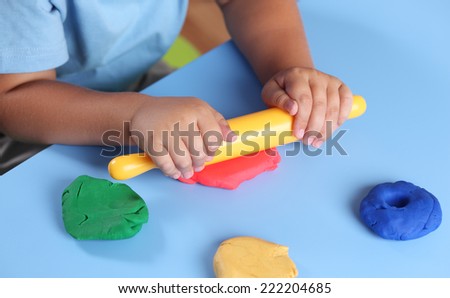 Children\'s hands with rolling-pin playing modeling clay.