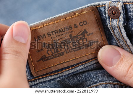 Tambov, Russian Federation- October 21, 2012: Woman\'s hand taking out label logo  from pocket of a pair Levi\'s Jeans. Studio shot. Levi Strauss &Co. is a American clothing company was founded in 1853.
