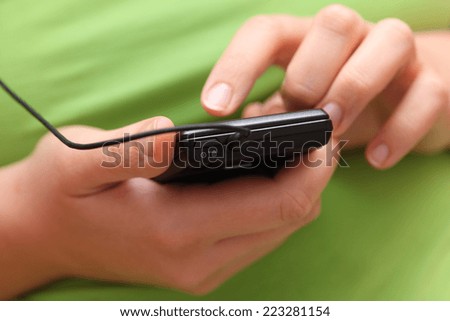 Woman using a smartphone with headset (Listening music). Close-up.