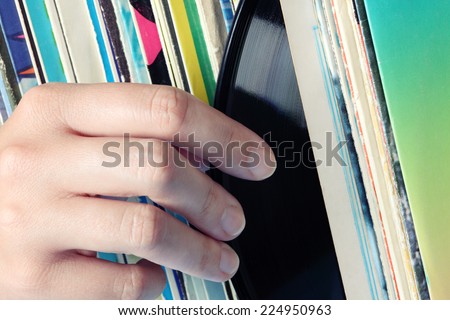 Woman\'s hand takes one record from the collection of old vinyl records.