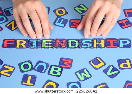 Word Friendship spell out on a desk with woman\'s hands and letters. Letters draw by myself.