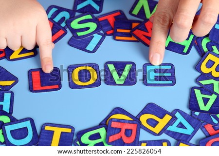 Word Love spell out on the desk with child\'s and mother\'s hands and letters. Letters drawn by me.