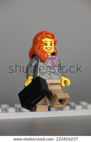 Tambov, Russian Federation - February 26, 2013: Lego businesswoman figure with black suitcase on grey background. Studio shot.