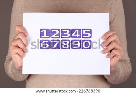Woman\'s hands hold page with drawing numbers from 1 to 0. Numbers drawn by me by ballpoint pens.