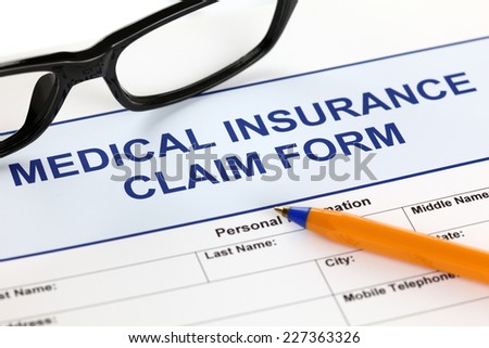 Medical insurance claim form with glasses and ballpoint pen.