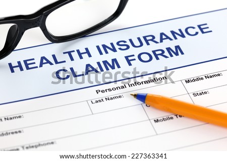 Health insurance claim form with glasses and ballpoint pen.